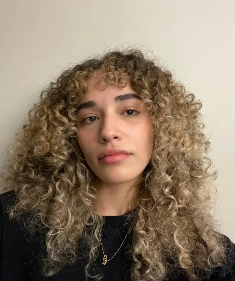 Retrato de Maria Luiza Silveira, de cabelo cacheado e blusa escura.
